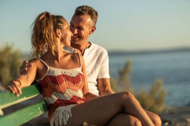 Sevgi dolu bir çift bankta oturuyor ve deniz kıyısında yaz tatilinin tadını çıkarıyorlar..