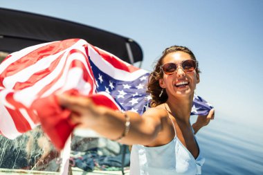 Amerikan bayrağıyla çekici genç bir kadın. Eğleniyor ve gününü özel yatında geçiriyor..