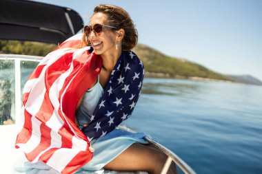 Amerikan bayrağıyla çekici genç bir kadın. Eğleniyor ve gününü özel yatında geçiriyor..