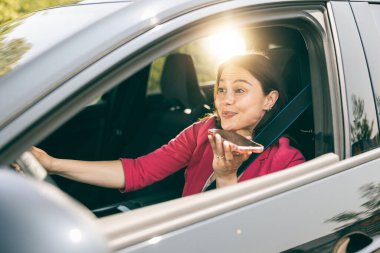 Genç bir kadın yeni arabasında telefonla konuşuyor..