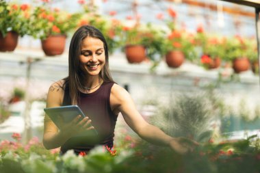 Serada duran ve tablet kullanan neşeli genç bir kadın..