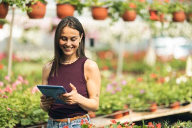 Serada duran ve tablet kullanan neşeli genç bir kadın..