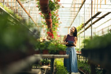 Serada duran ve tablet kullanan neşeli genç bir kadın..