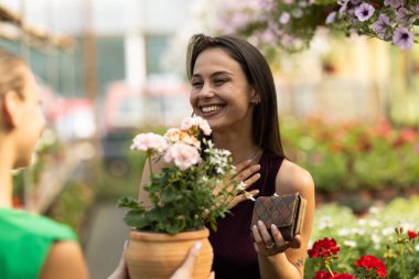 Mutlu ve gülümseyen müşteri seradan çiçek alıyor..