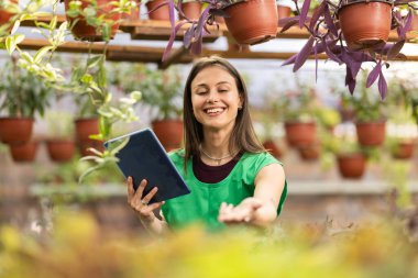 Tabletini kullanırken çiçekçide çalışan neşeli bir kadın..