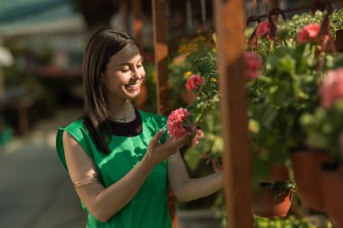 Kadın bahçe işçisi serada çiçeklerin tadını çıkarıyor..