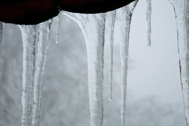 Çatıda buz saçakları asılı. Kış doğası soyut sanat. Fiziksel fenomen, katı su formu..