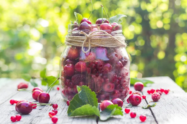 Tarro de vidrio lleno de frutas cerezas y frambuesas — Foto de Stock