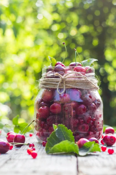 Glass jar full of fruits cherries and raspberries — Stock Photo, Image