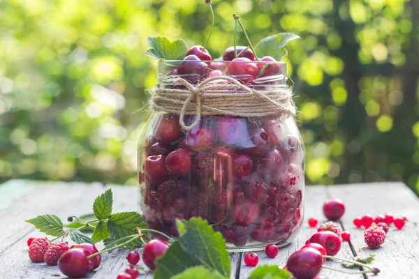 Vaso di vetro pieno di ciliegie e lamponi — Foto Stock