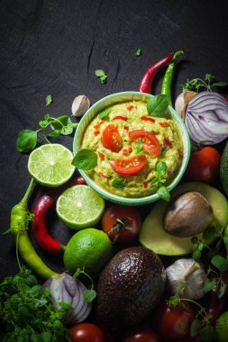Arka plan ile guacamole ve malzemeler: domates, biber biber, kireç, soğan, sarımsak, dereotu ve kekik