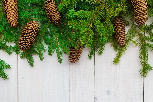 Boże Narodzenie tło świerkowe gałązki szyszki biały drewniany — Zdjęcie stockowe