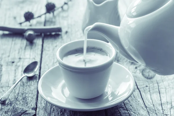 Pouring milk from jug cup black coffee — Stock Photo, Image