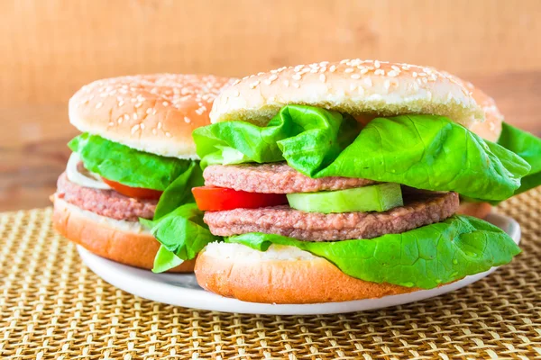 Två hemgjorda grillade hamburgare trä matta — Stockfoto