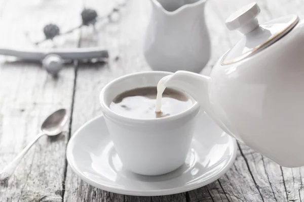 Pouring milk from jug cup black coffee — Stock Photo, Image