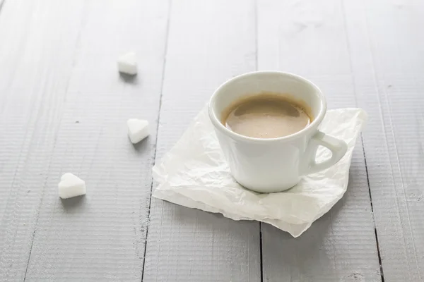 Coffee cup with milk and sugar cubes scattered — Stock Photo, Image