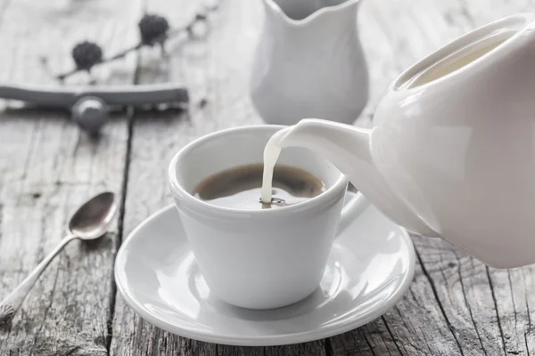 Verter leche de la taza de jarra de café negro — Foto de Stock