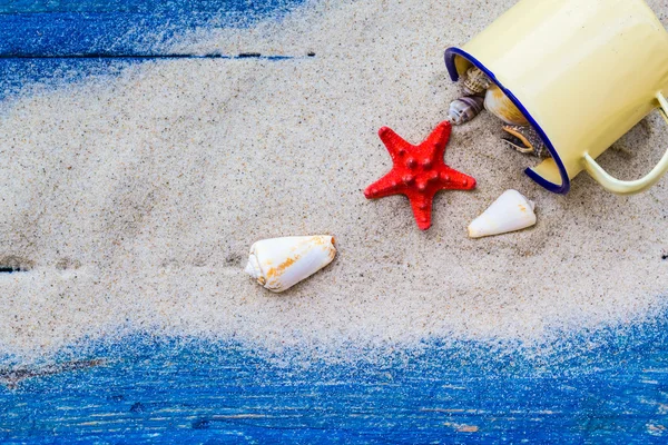 Coquilles colorées tasse sable planches bleues éparpillées — Photo