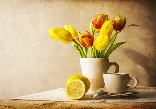 Still life bouquet yellow tulips cup of tea — Stock Photo, Image