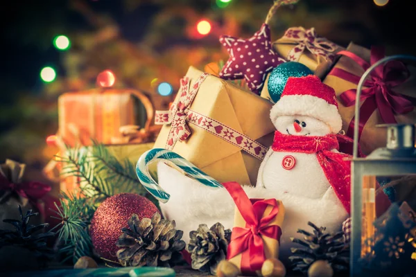 Sněhulák vánoční přání, ozdoby dary stromu osvětlení pozadí — Stock fotografie