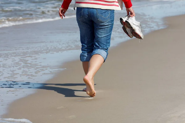 一个在海滩上散步的放松女人的后视镜照片 图库图片