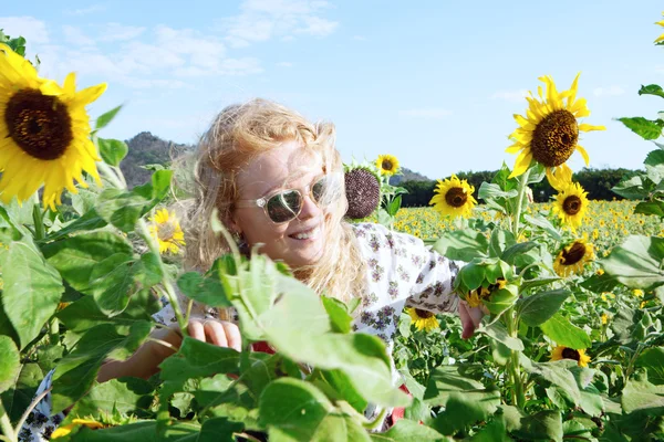 Porträtt av ung leende glad kvinna att få igenom fältet solros — Stockfoto