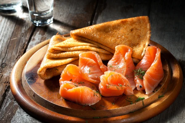 Vista di belle crepes calde fresche con salmone affumicato su sfondo di colore — Foto Stock