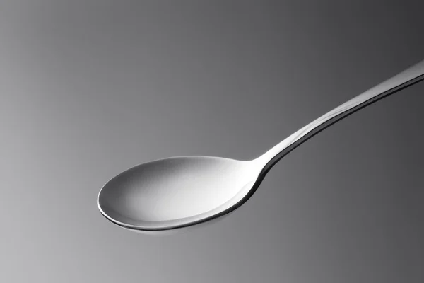 Close up macro view of nice metal spoon on grey back — Stock Photo, Image