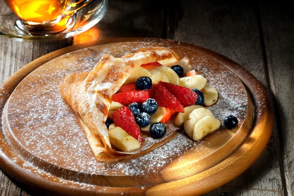 Blick auf schöne frische heiße Crêpes mit Beeren auf farbigem Hintergrund — Stockfoto