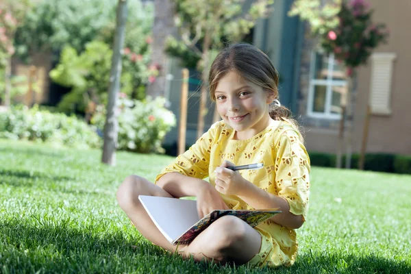 Retrato de menina estudando na grama no ambiente de verão — Fotografia de Stock