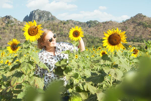 Retrato de una joven sonriente mujer feliz atravesando el campo de girasol —  Fotos de Stock