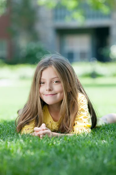 Portrait of little girl laying on the grass in summer environment — Stock Photo, Image