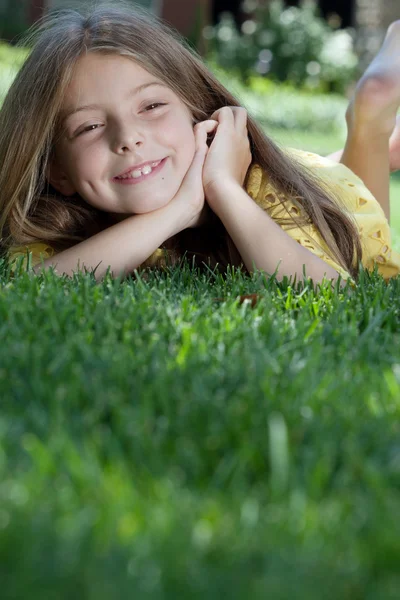 Portrait of little girl laying on the grass in summer environment — Stock Photo, Image