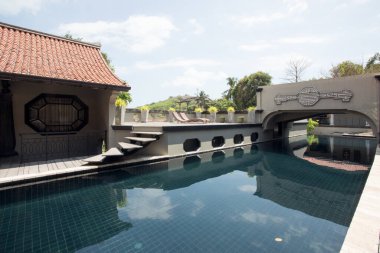 Etrafı çimen ve kiremitlerle kaplı tropik yüzme havuzu manzarası