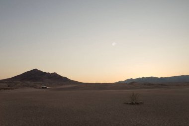 Gün batımında panoramik manzaralı ölüm vadisi çölü arabalı ve sırtında bazı dağlar