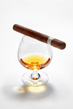 Kapalı bir viski bardağı manzarası, üstünde beyaz bir puro.