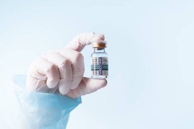 Logo ya da tuzak izi yok! SİZE LABELS yaptı! Doktorların elinin mavi sırtında bir ampul kovid aşıyla görüntüsünü kapat.