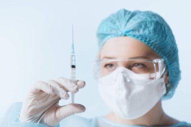 Doktorun mavi sırtında bir şırınga şırıngası olan görüntüsünü kapat.
