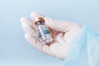 Logo ya da tuzak izi yok! SİZE LABELS yaptı! Doktorların elinin mavi sırtında bir ampul kovid aşıyla görüntüsünü kapat.