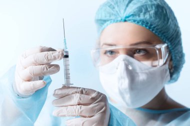 Doktorun mavi sırtında bir şırınga şırıngası olan görüntüsünü kapat.
