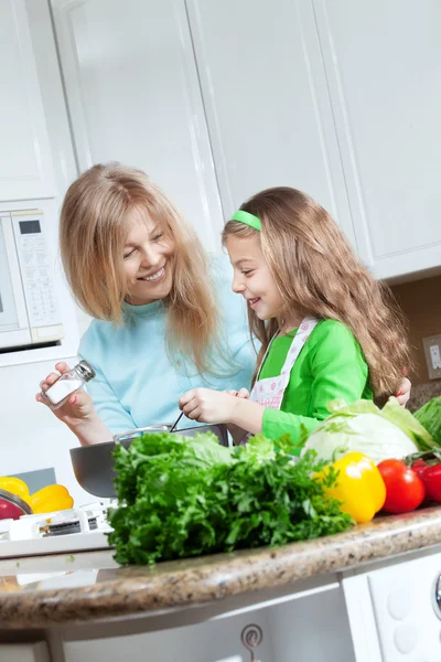 View of young beautiful girl cooking at the kitchen with her mamaview of young beautiful girl cooking at the kitchen with her mama — Stock Photo, Image