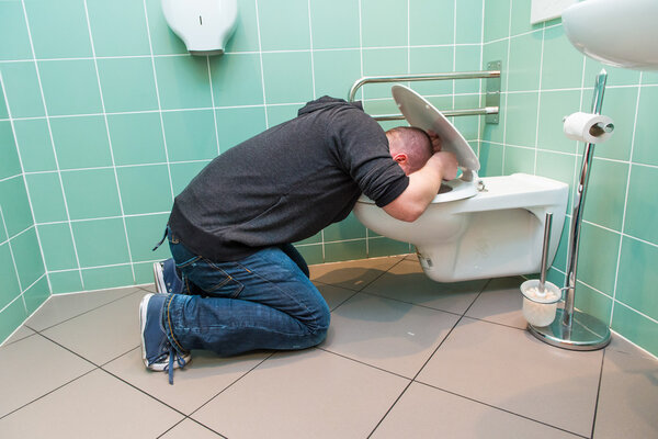 man vomiting in the toilet