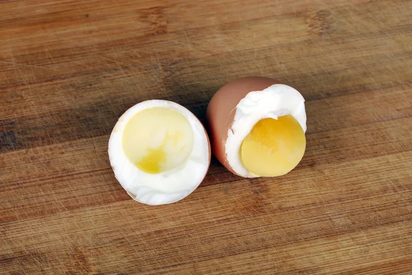 two halves of boiled egg with one half is without  the yolk and the second half  is filled with yolk on the background of a natural wooden board