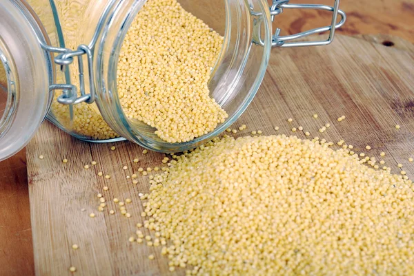 Jar with millet on a wooden background — Stock Photo, Image