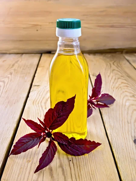 Aceite con amaranto en botella sobre tabla ligera —  Fotos de Stock