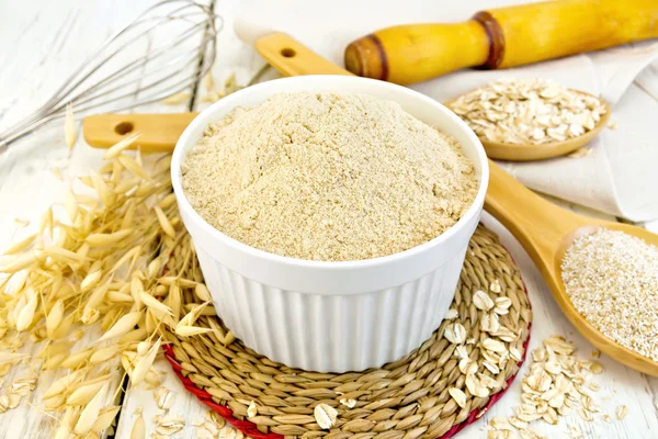 Harina de avena en tazón blanco sobre tabla ligera — Foto de Stock