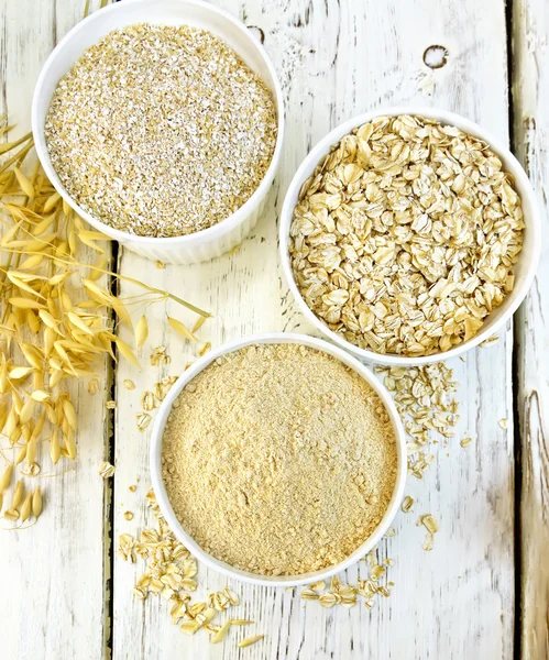 Flour oat in white bowl with bran and flakes on board top — Stock Photo, Image