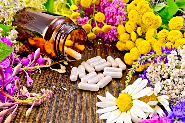 Capsules in brown jar with flowers on board — Stock Photo, Image
