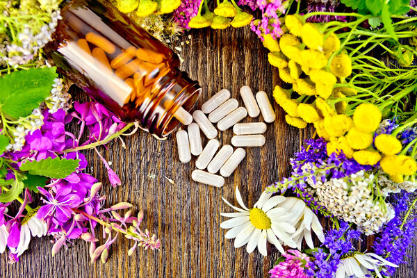 Capsules in brown jar with flowers on board top