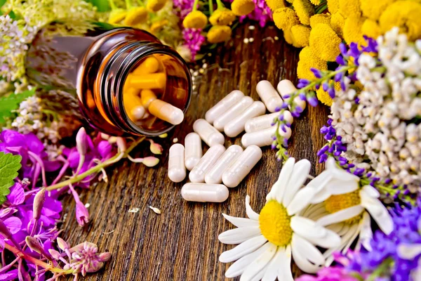 Capsules in open brown jar on board with flowers — Stock Photo, Image